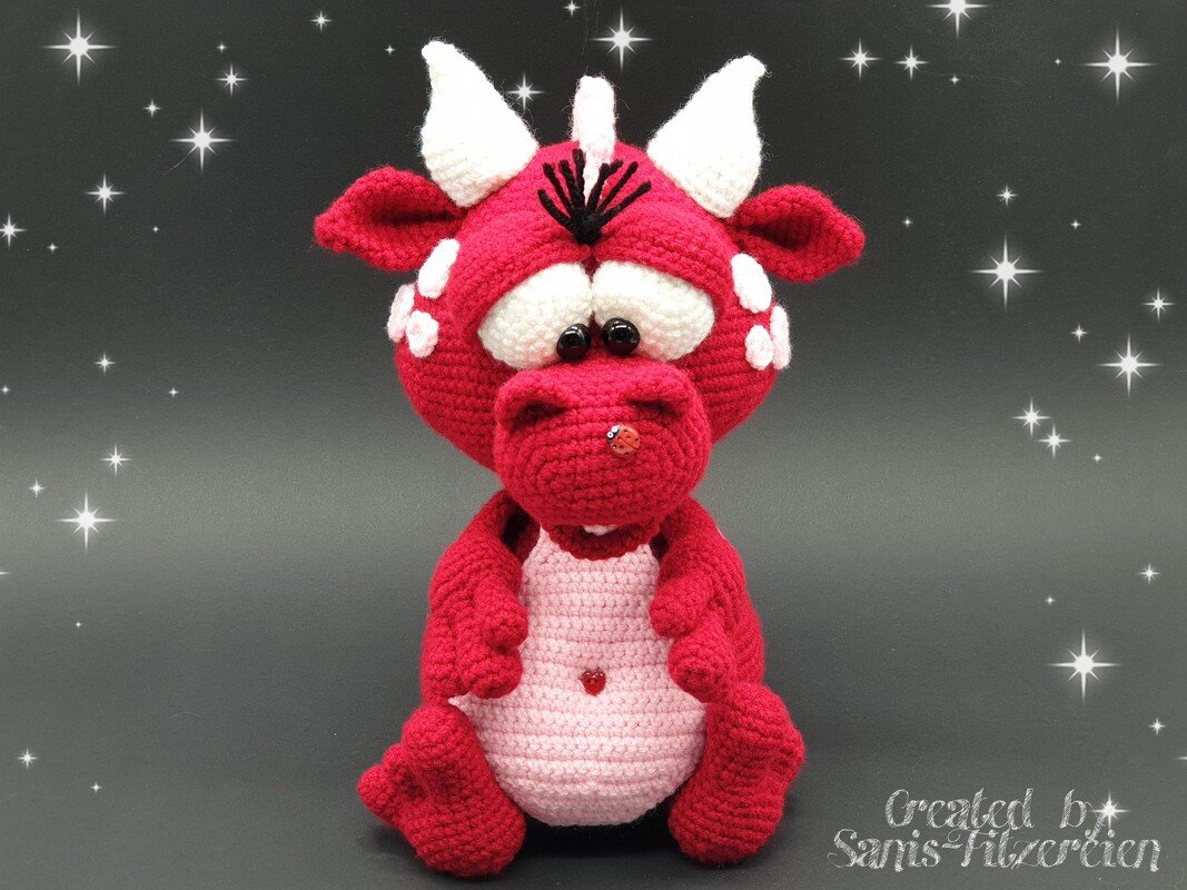 Roter gehäkelter Amigurumi-Drache mit weißen Hörnern und rosa Bauch