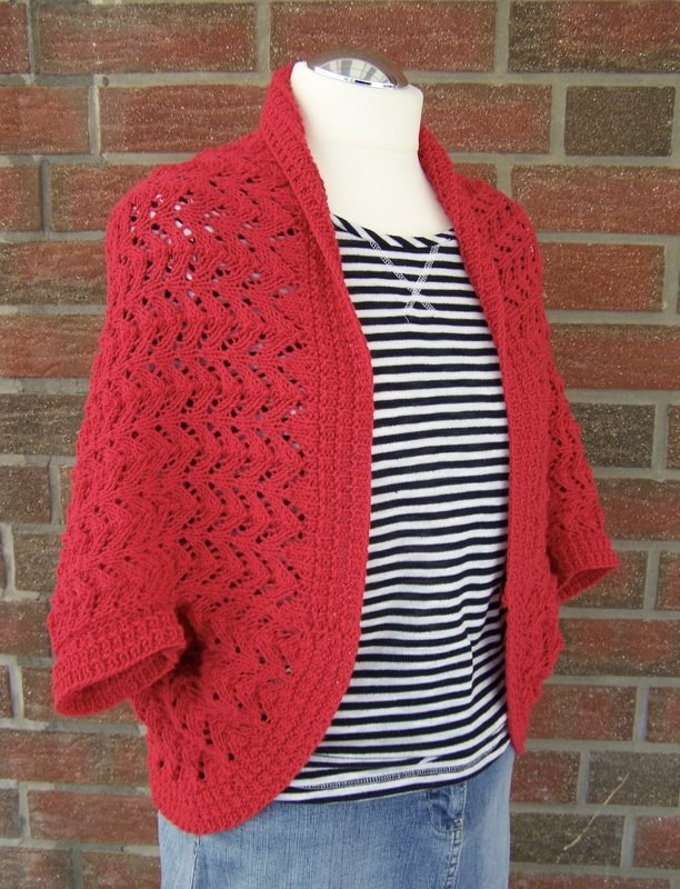 Roter gestrickter Seelenwärmer mit Ajourmuster auf Schaufensterpuppe über gestreiftem Shirt