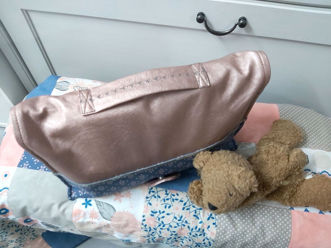 Roségoldene Utensilo-Tasche mit blauem Blumenstoff auf Patchwork-Decke neben Teddybär