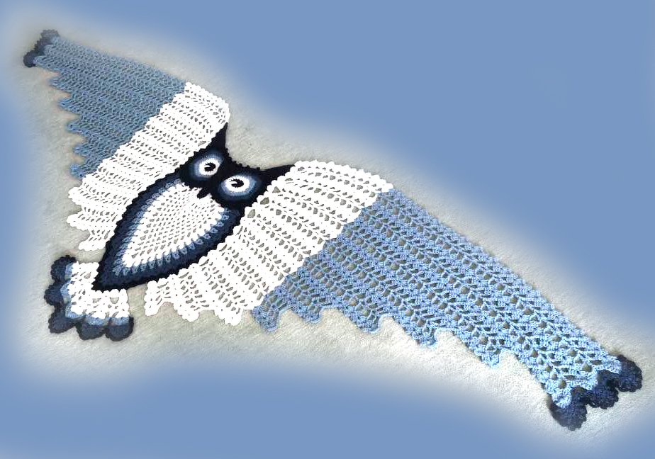 Light blue and white crocheted triangle shawl with central owl motif and scalloped edges