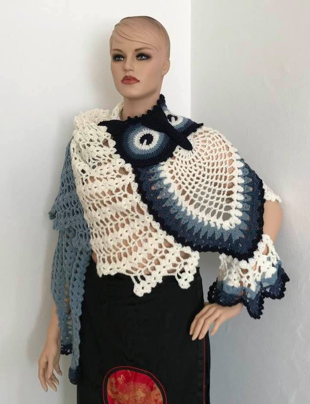 Mannequin wearing cream triangle crochet shawl with navy-to-light-blue ombre owl motif corner and scalloped edges