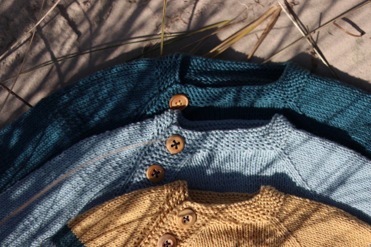 Three layered knitted baby sweaters in teal, light blue and mustard with wooden buttons