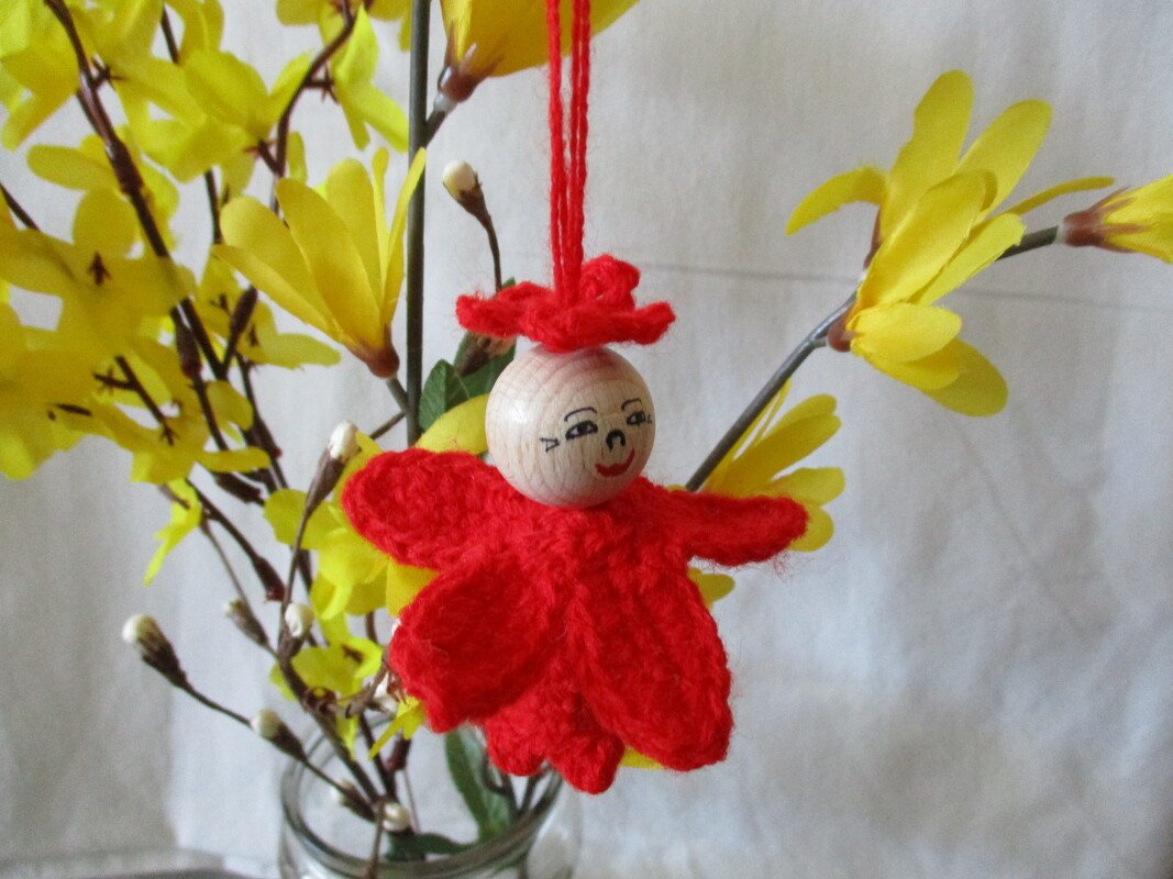 Gehäkelter roter Blumenanhänger mit Holzperlenkopf an gelben Zweigen