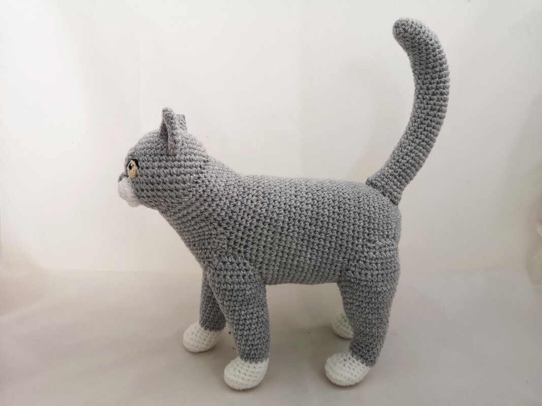 Gray crocheted amigurumi cat with white paws and upright tail