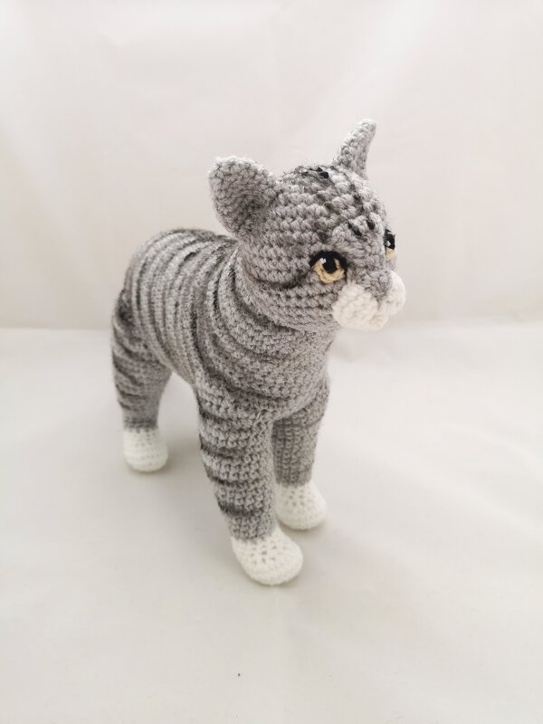 Gehäkelte graue gestreifte Amigurumi-Katze mit weißen Pfoten