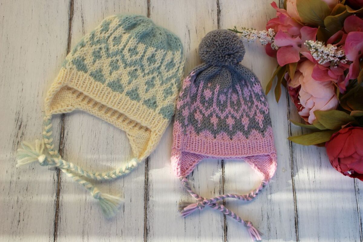 Two knitted baby earflap hats, blue-cream and pink-gray, with braided ties