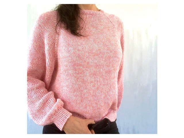 Woman wearing a pink raglan crewneck knit sweater with ribbed cuffs