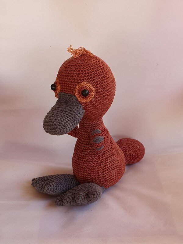 Gehäkeltes Amigurumi in Terrakotta mit grauem Schnabel und grauen Füßen