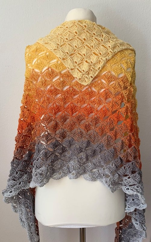 Gehäkeltes Dreieckstuch mit Muschelmuster und Farbverlauf in Gelb-Orange-Grau auf Schaufensterpuppe
