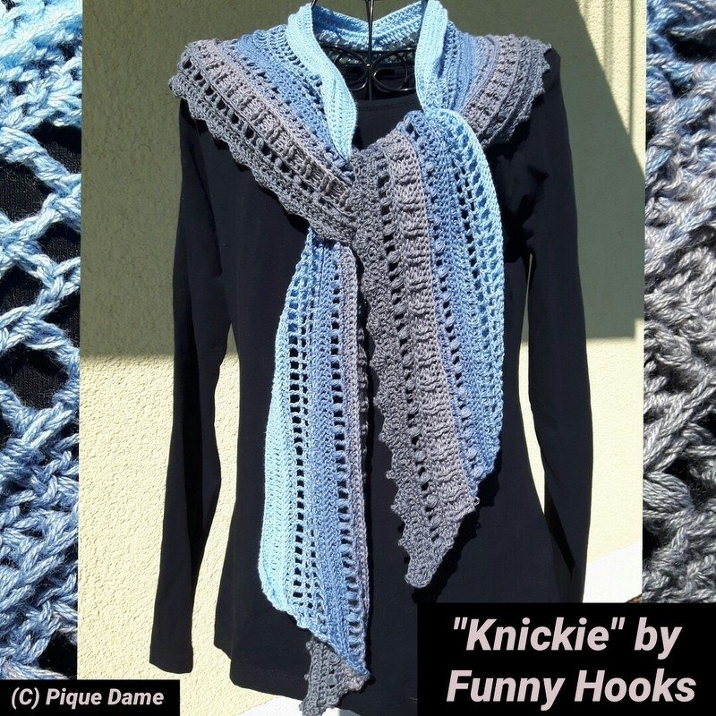 Two-toned crocheted scarf in light blue and grey with openwork and textured stitches on a black mannequin top.