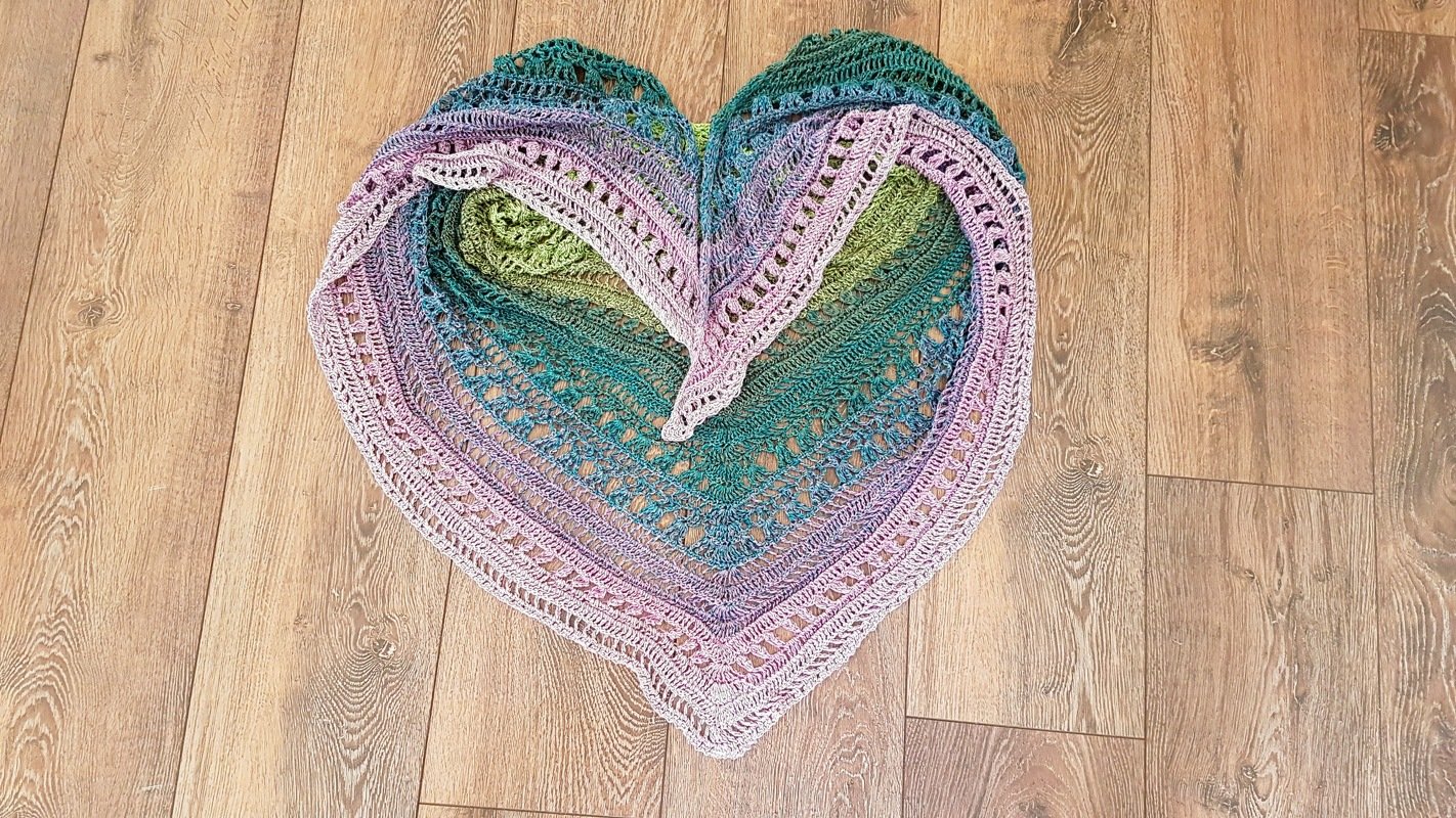 Dreieckstuch gehäkelt mit Ombré-Farben in Herzform auf Holzfußboden