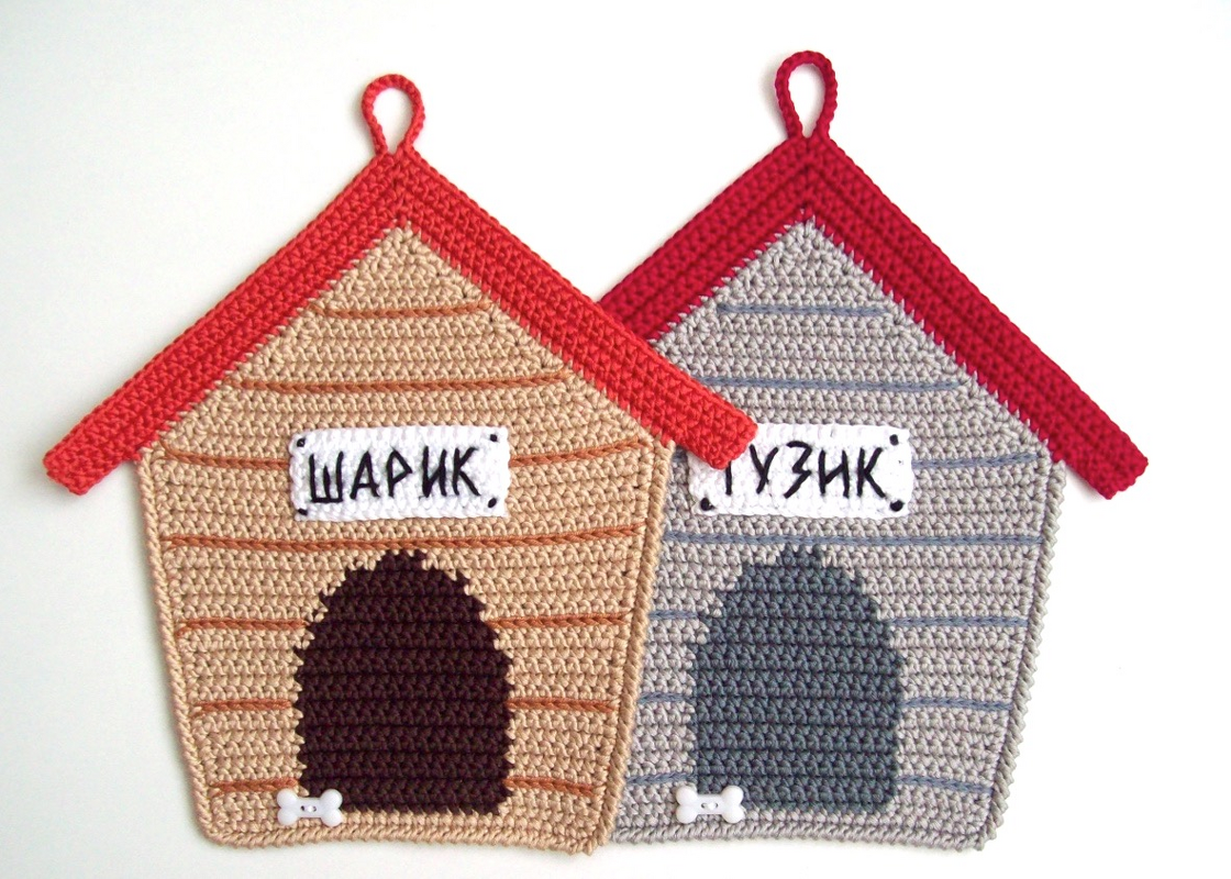 Zwei gehäkelte Topflappen in Hundehäuschen-Form, beige und grau, mit rotem Dach, Aufhängeschlaufe und kyrillischem Namensschild