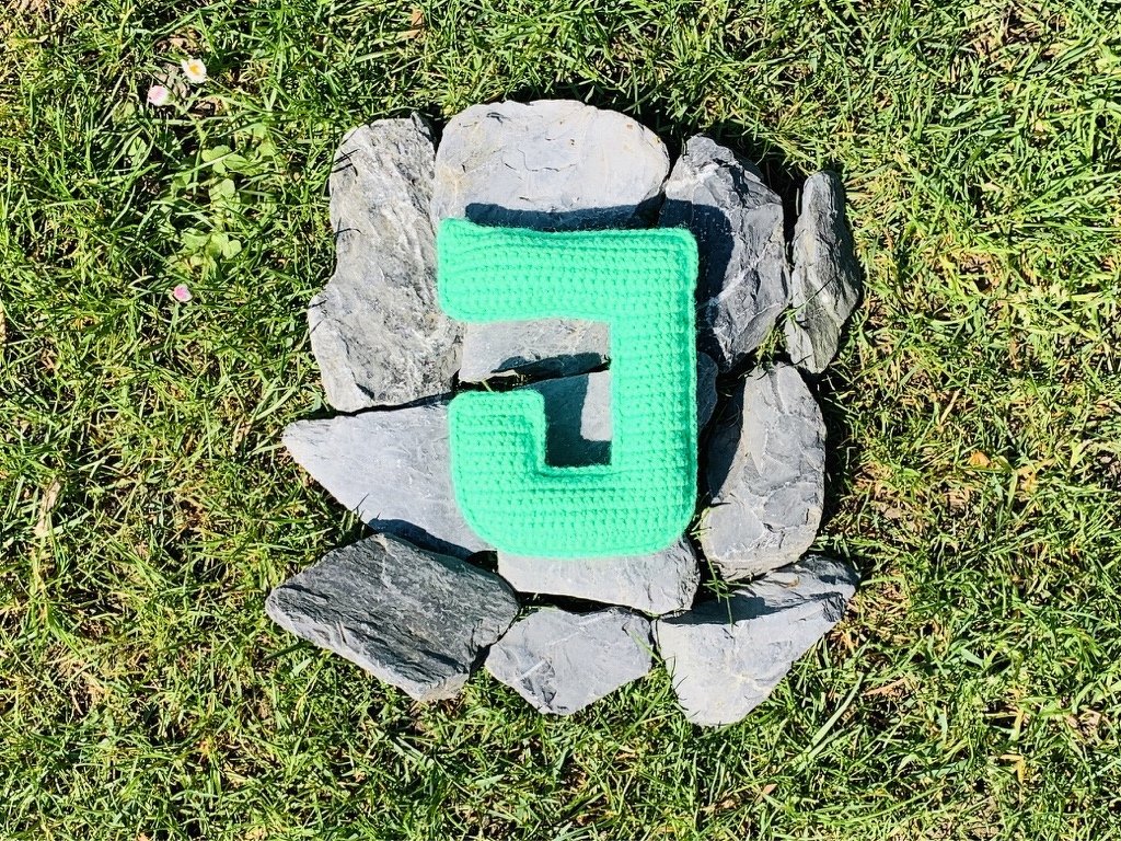 Gehäkelter Buchstabe J in Mint auf Schiefer