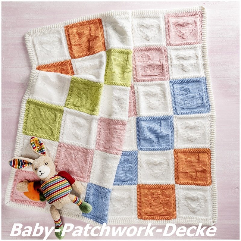 Gestrickte Babydecke aus quadratischen Patchwork
Feldern mit erhabenen Herz- und Sternmotiven in Pastellfarben, weißer Rand und Stoffhase daneben
