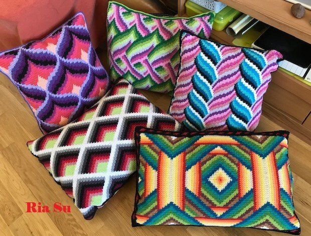 Fünf gehäkelte Kissen mit bunten geometrischen Mustern