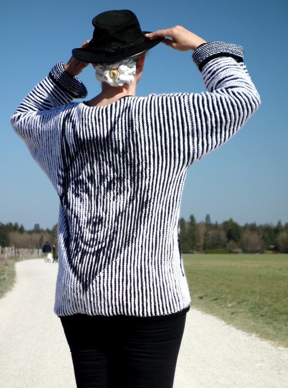 Rückenansicht einer schwarz-weiß gestreiften Strickjacke mit Blumenmotiv