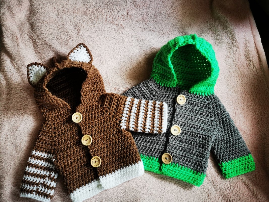 Zwei gehäkelte Babyjacken: braun mit Bärenohren und grau mit grüner Kapuze