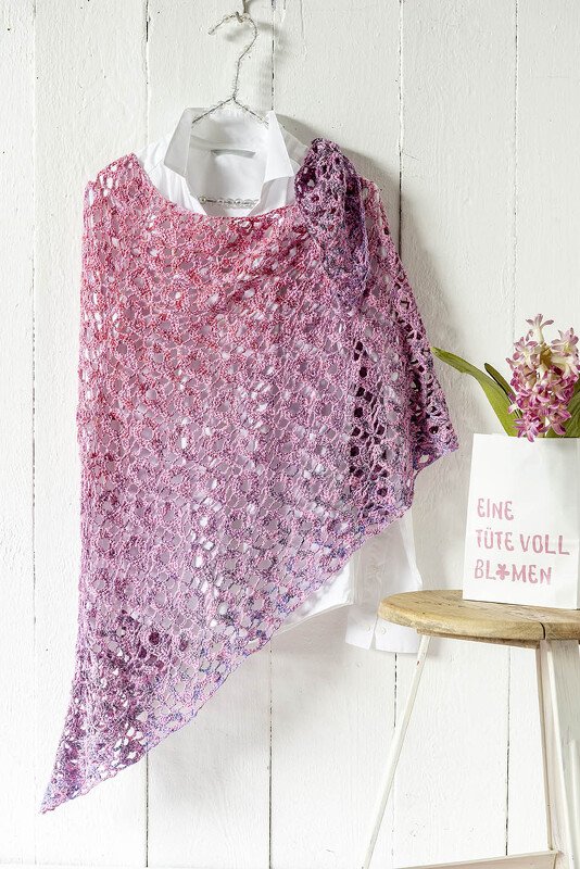 Gehäkeltes Dreieckstuch in Pink‑Lila‑Farbverlauf mit Spitzenmuster, drapiert über weißem Hemd an einem Bügel