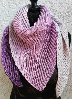 Gehäkeltes Dreieckstuch in Rosa- und Lilatönen mit markanter Rippenstruktur, auf einer Büste drapiert