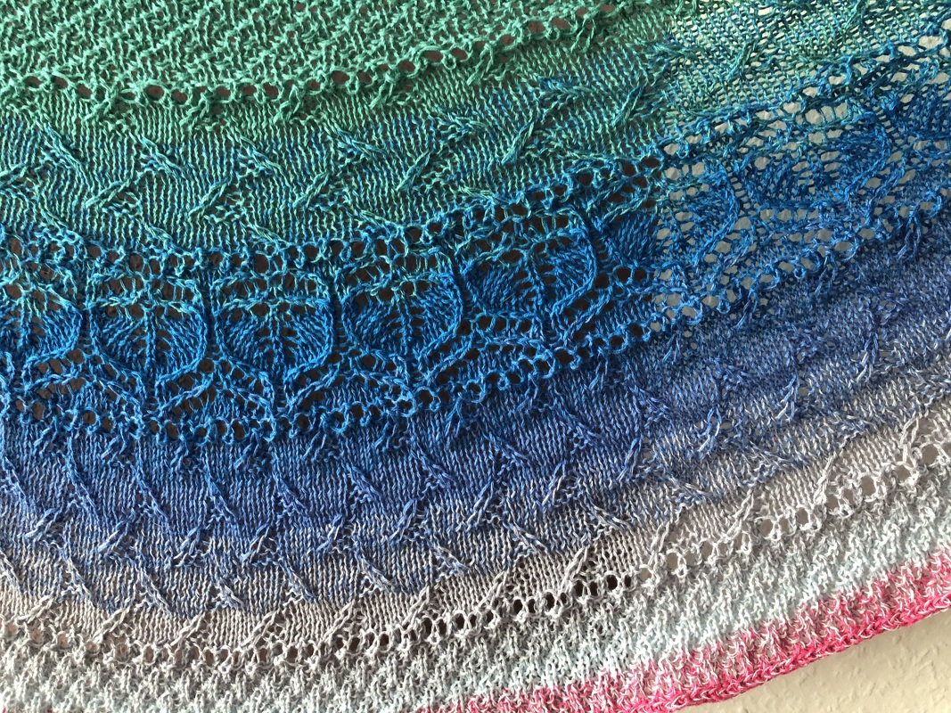 Halbrundförmiges gestricktes Tuch in Grün-, Blau- und Rosatönen mit Ajour- und Strukturmustern