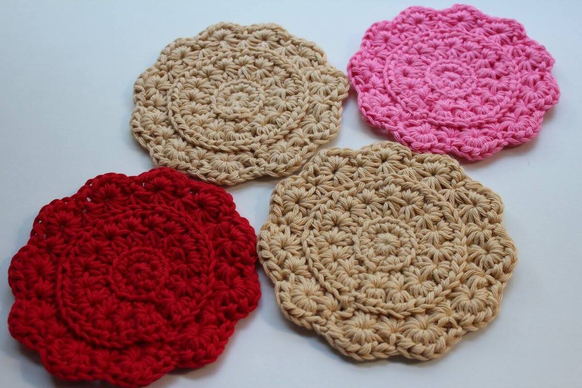 Vier gehäkelte runde Untersetzer in Beige, Rot und Rosa auf hellem Hintergrund