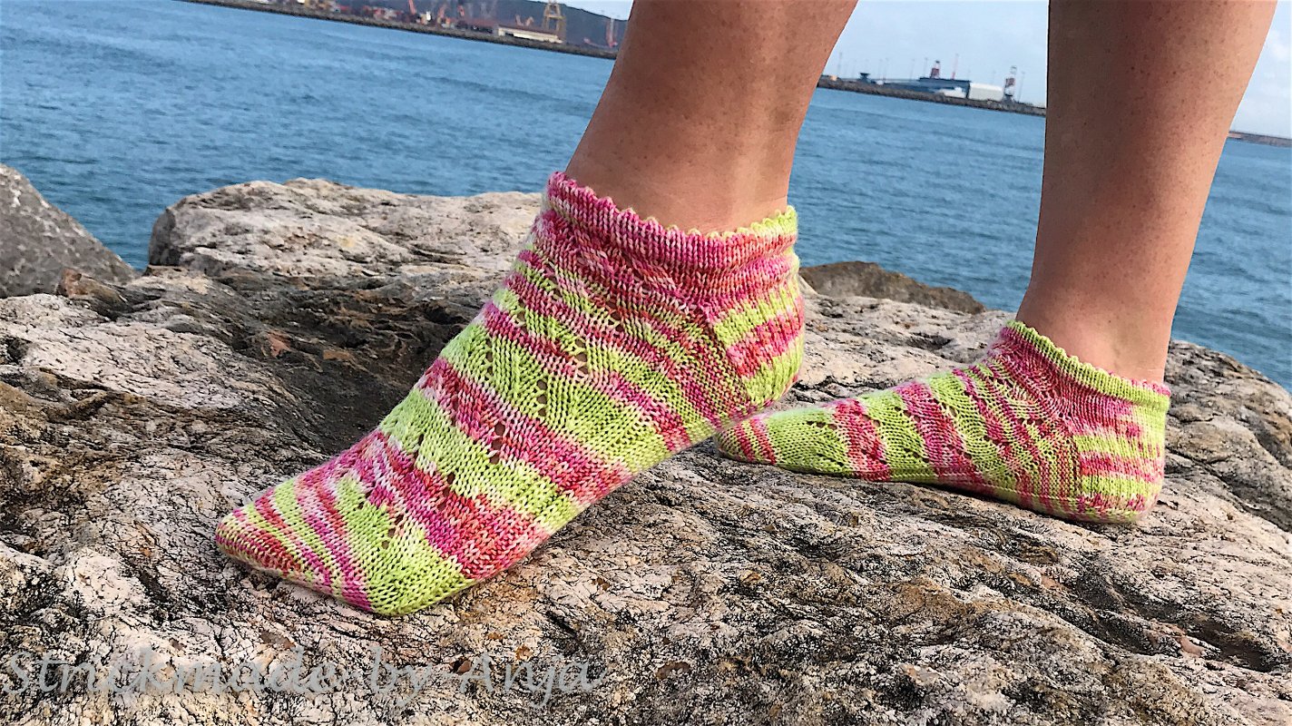 Gestrickte knöchelhohe Socken in Pink und Neongrün auf Felsen