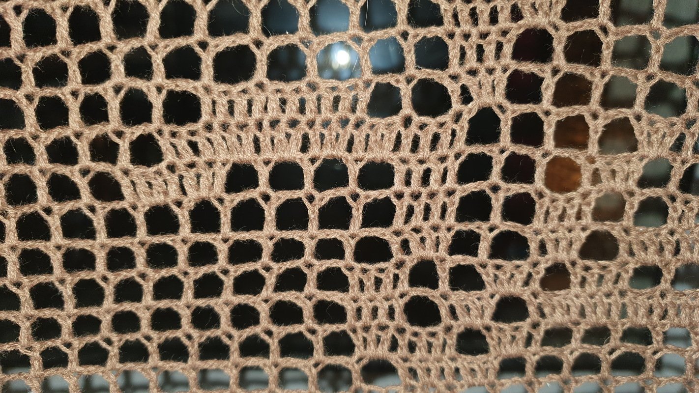 Detail eines beigen, gehäkelten Lochmusters