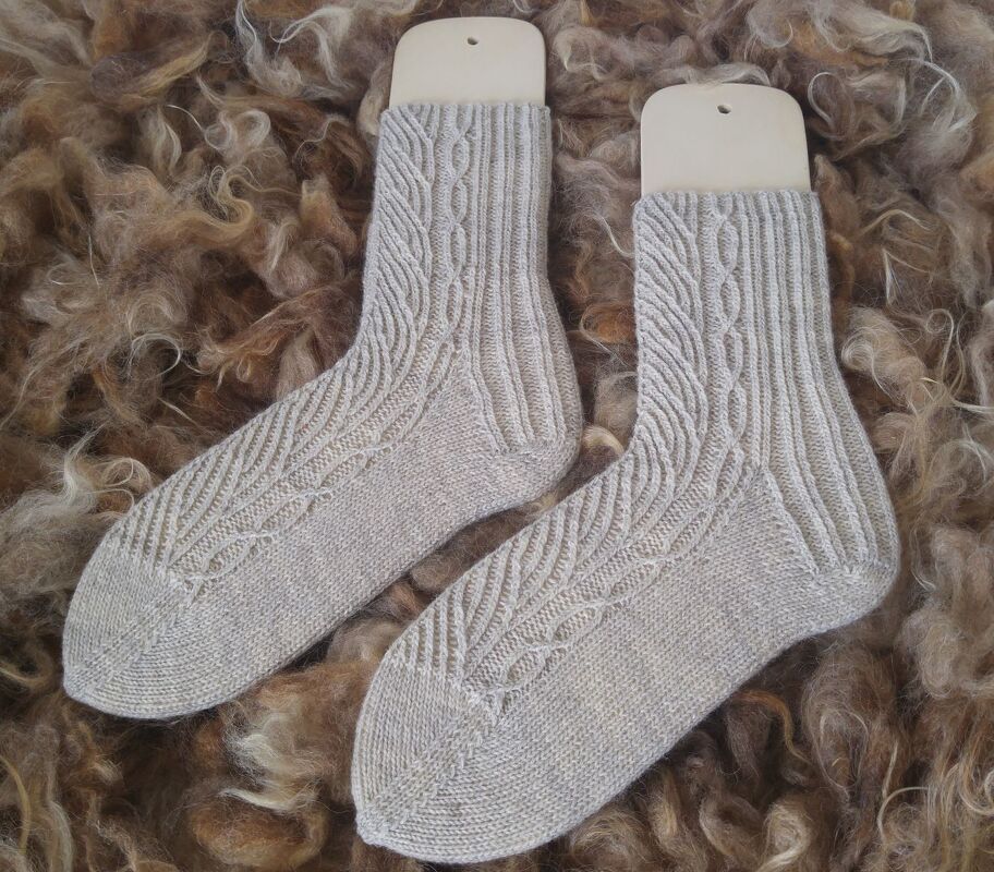 Beige gestrickte Damensocken mit Zopfmuster auf Sockenformern auf Wollfleece