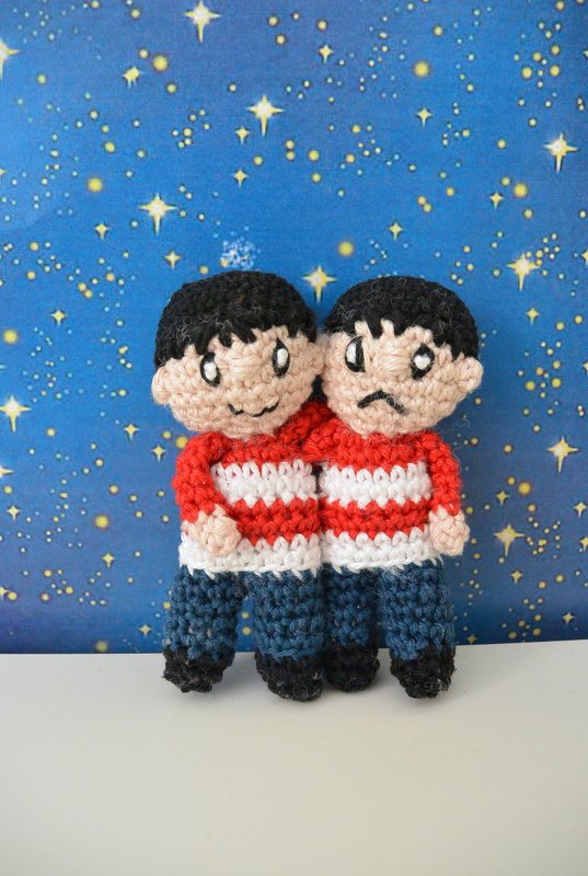 Zwei gehäkelte Mini-Figuren nebeneinander mit rot-weißen Streifenpullovern und unterschiedlichen Gesichtsausdrücken