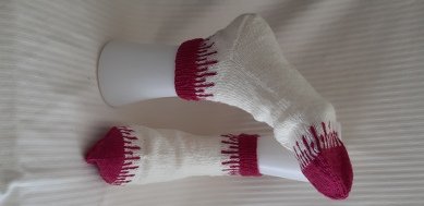 Weiße Socken mit magentafarbener Ferse und Spitze; eine Socke auf einer Fußform, eine flach ausgelegt