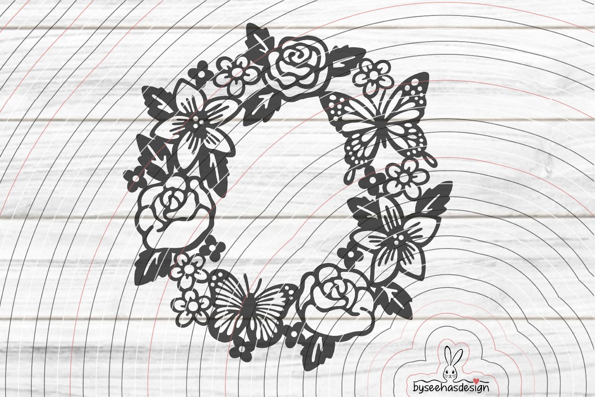 Schwarze Silhouette eines runden Blumenkranzes mit Rosen, Blüten und Schmetterlingen auf hellem Holzgrund.