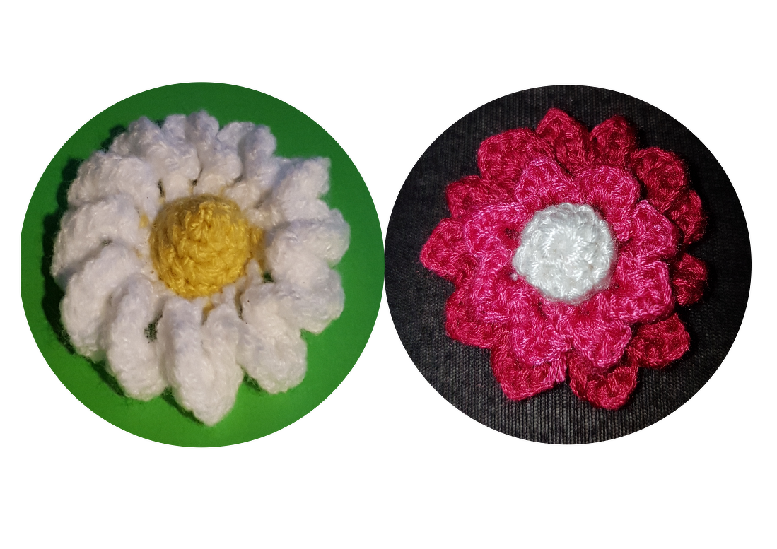 Zwei gehäkelte Blumen, weiße Margerite mit gelbem Kern und pinkfarbene Blüte mit weißer Mitte.