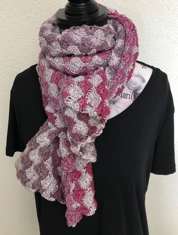 Gehäkelter Schal in Rosé und Grau mit Muschelmuster, an einer Schaufensterpuppe drapiert
