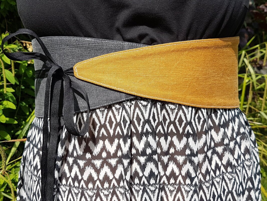 Breiter obi-ähnlicher Gürtel in Grau und Senfgelb mit Bindebändern über gemustertem Rock