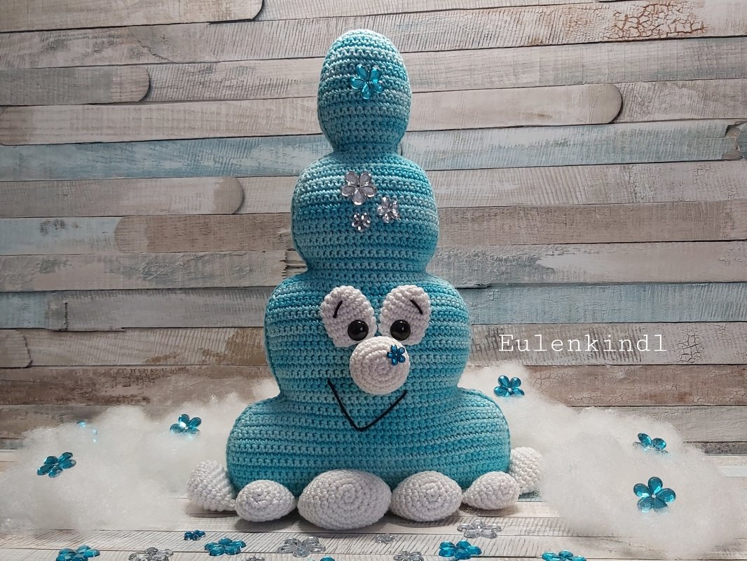 Dreiteiliges türkis-weißes Amigurumi mit weißen Applikationen und blauen Blumenakzenten