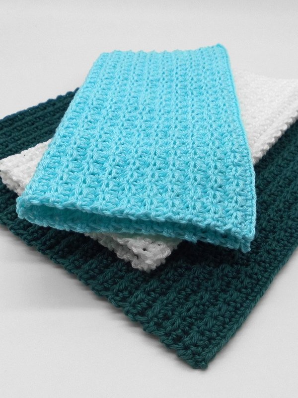 Three stacked rectangular crochet potholders in teal, white, and aqua showing ribbed stitch texture