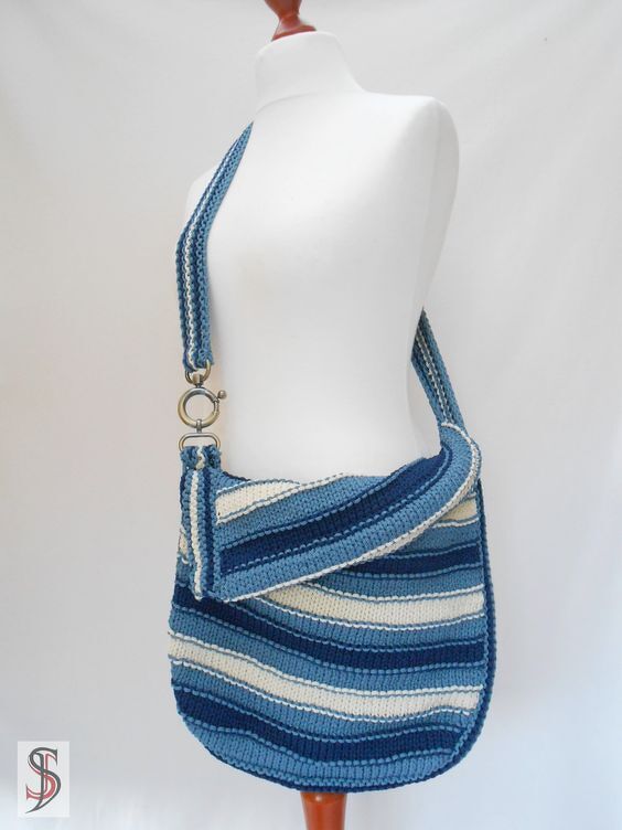 Gestrickte Umhängetasche blau-weiß gestreift mit breitem Träger und Metallringen an einer Schaufensterpuppe