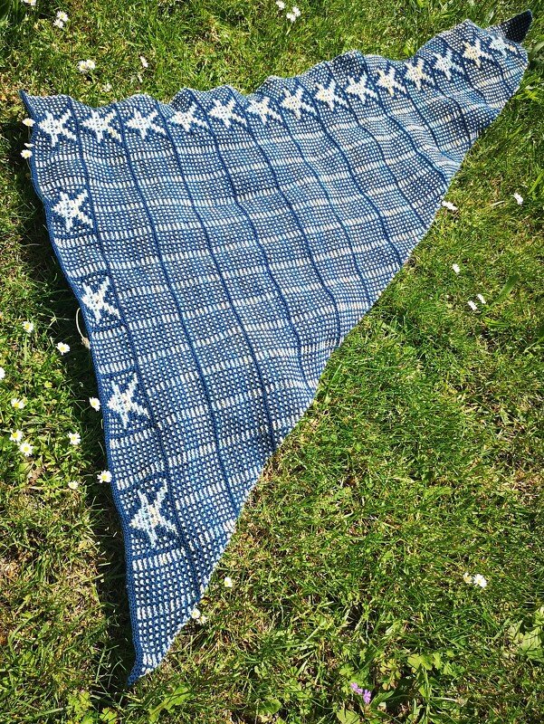 Nahaufnahme eines gestrickten Dreieckstuchs mit Karomuster und weißen Sternen