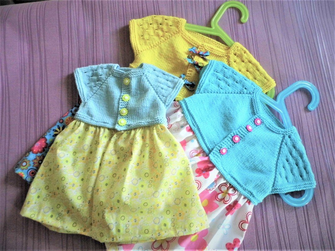 Drei Babykleidchen mit Knopfleiste, Raglan‑Schultern und Lochmuster