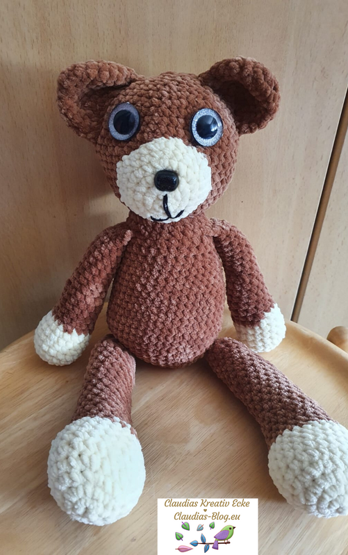 Gehäkelter brauner Amigurumi-Teddy mit cremefarbener Schnauze und Pfoten, sitzend