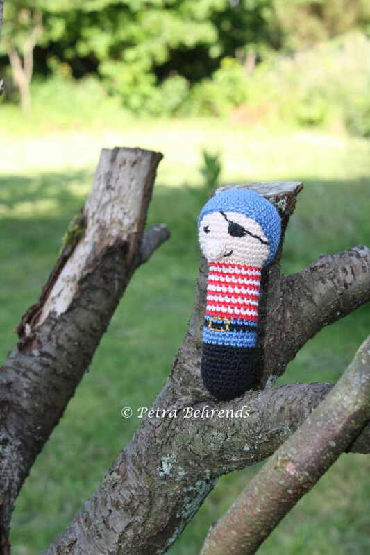 Gehäkelte Piraten-Greiffigur mit blauem Mützchen auf einem Baumast