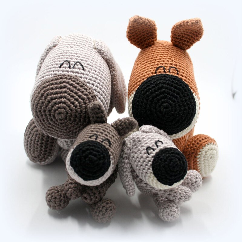Vier gehäkelte Amigurumi-Hunde in Braun- und Grautönen, zwei größere hinten, zwei kleinere vorn.