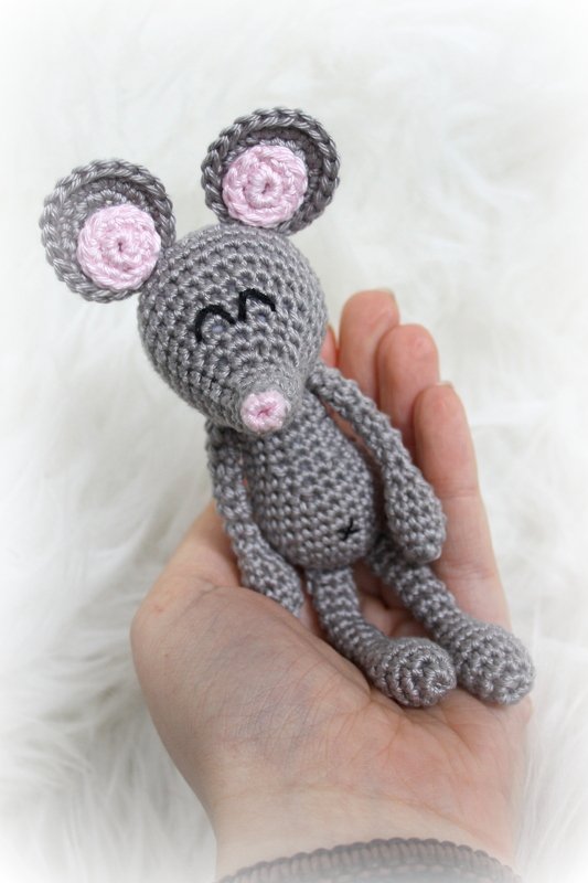 Hand hält kleine gehäkelte Amigurumi‑Maus in Grau mit rosa Ohren