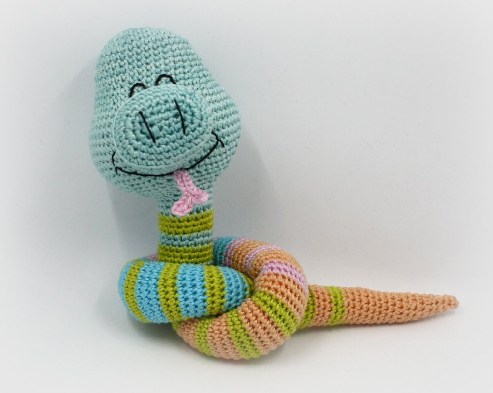 Gehäkelte Amigurumi‑Schlange, hellblauer Kopf, pastellgestreifter Körper, rosa Zunge