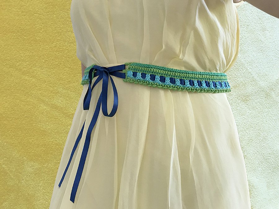 Gehäkelter grüner und blauer Taillengürtel mit blauem Satinband an cremefarbenem Kleid