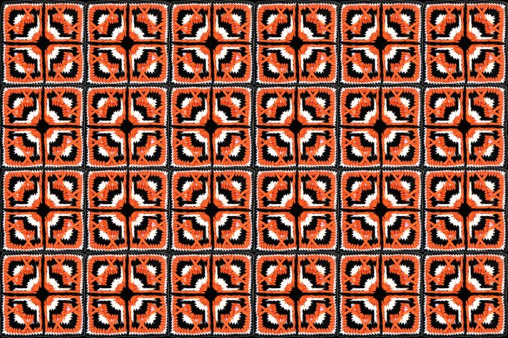 Mehrere zusammengenähte gehäkelte Quadrate in Orange, Schwarz und Weiß mit geometrischem Muster