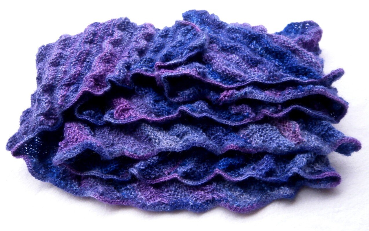 Folded purple and blue knitted scarf with ruffled wavy edges
