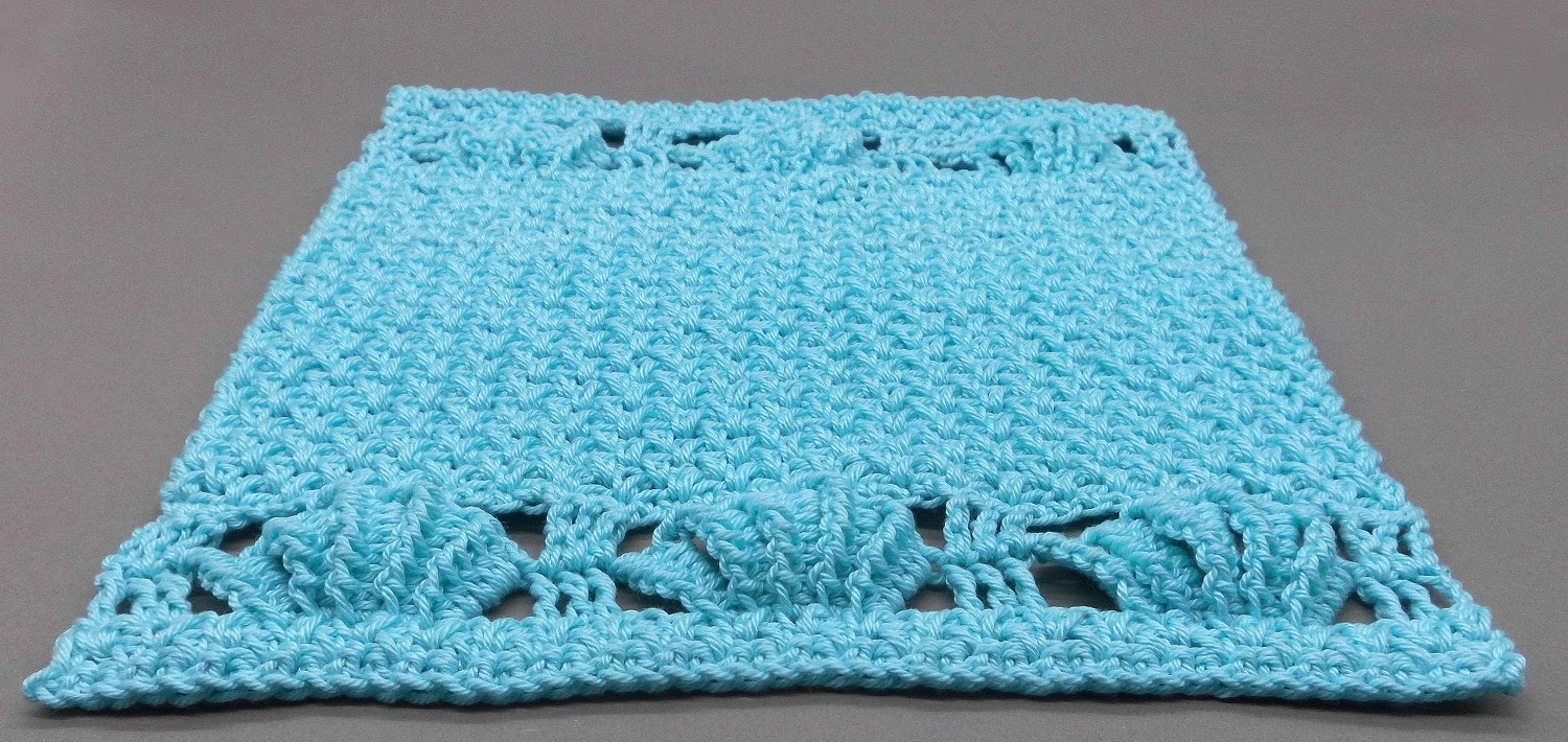 Hellblaues gehäkeltes Rechteck mit Noppenbordüre auf grauem Hintergrund