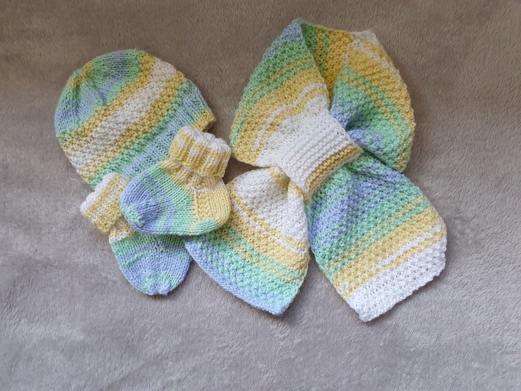 Gestricktes Baby-Set mit gestreifter Mütze, Schal und Söckchen in Pastellfarben auf hellem Hintergrund.
