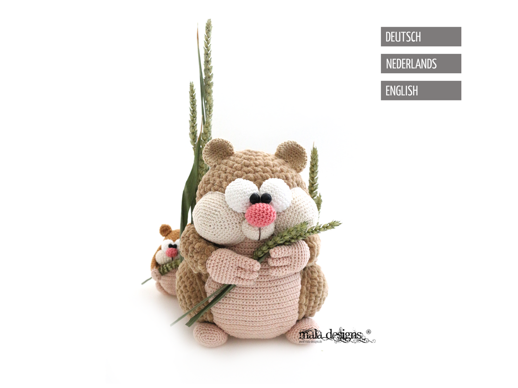 Beige and pink crocheted rodent amigurumi holding wheat stalks with a smaller matching toy behind on a white background